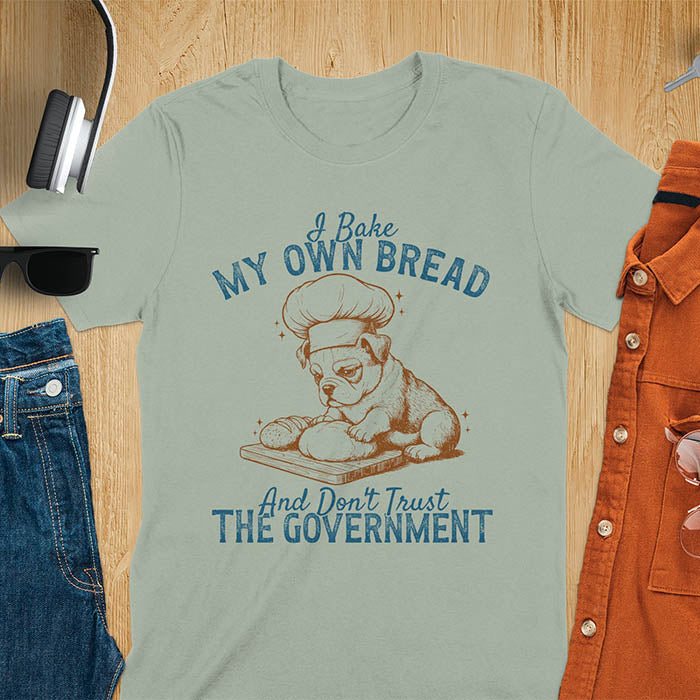 Sage green tee with "I Bake My Own Bread Don't Trust Government" text and vintage bulldog puppy in chef hat kneading bread graphic