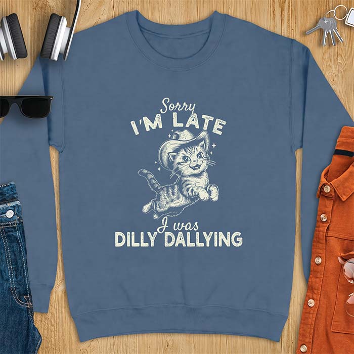 Indigo Blue sweatshirt with a graphic of a kitten wearing a cowboy hat leaping through the air with sparkle accents and the text Sorry I'm Late I Was Dilly Dallying