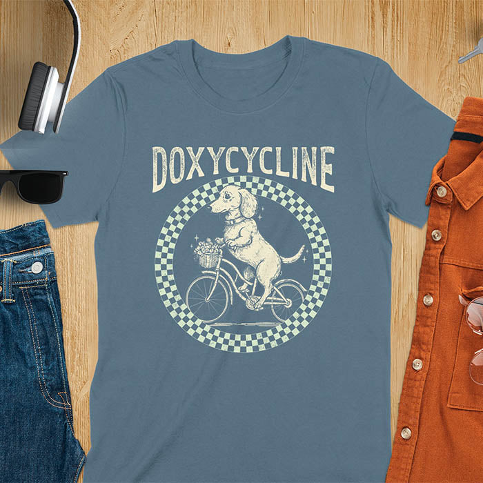 Indigo Blue Dachshund t-shirt with 'DOXYCYCLINE' text and cute wiener dog riding bicycle in checkered circle design