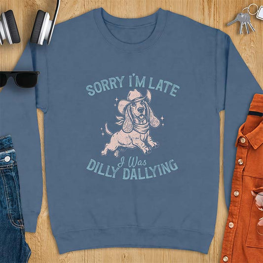Indigo Blue sweatshirt with a graphic of a basset hound wearing a cowboy hat and bandana trotting with sparkles around it and the text Sorry I'm Late I Was Dilly Dallying