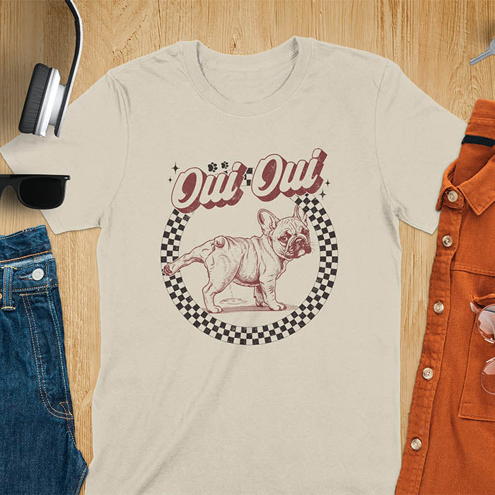 French Bulldog Oui Oui pun t-shirt with checkered circle border and retro script lettering on sand color tee