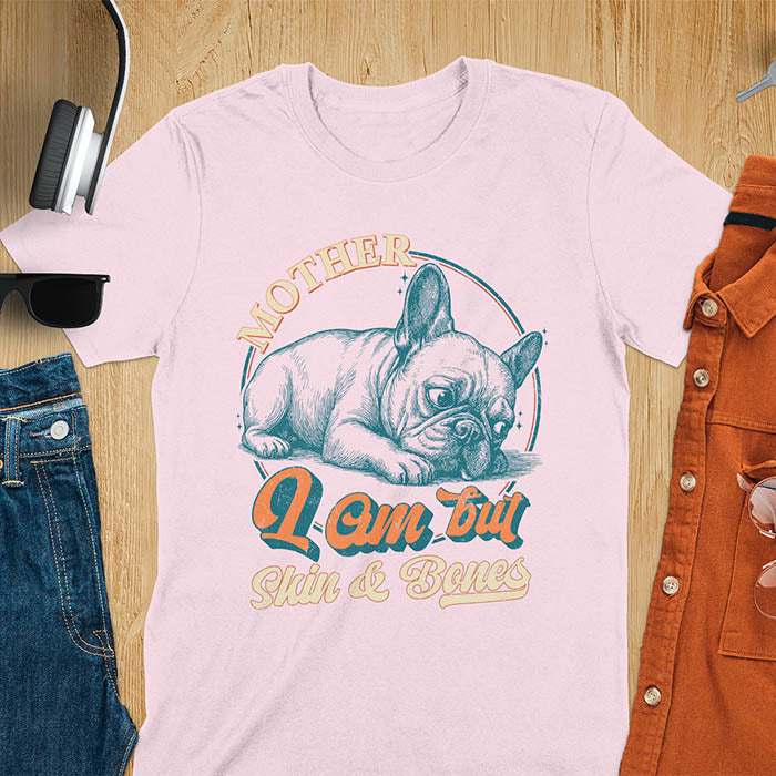 French Bulldog lying down with a sulky expression, with the text Mother I Am But Skin and Bones in retro typography on a light pink t-shirt