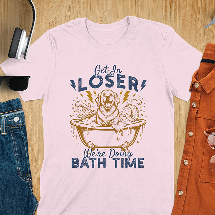 Golden Retriever sitting in a bathtub with soap bubbles and lightning bolts, with the text Get In Loser We're Doing Bath Time on a light pink t-shirt