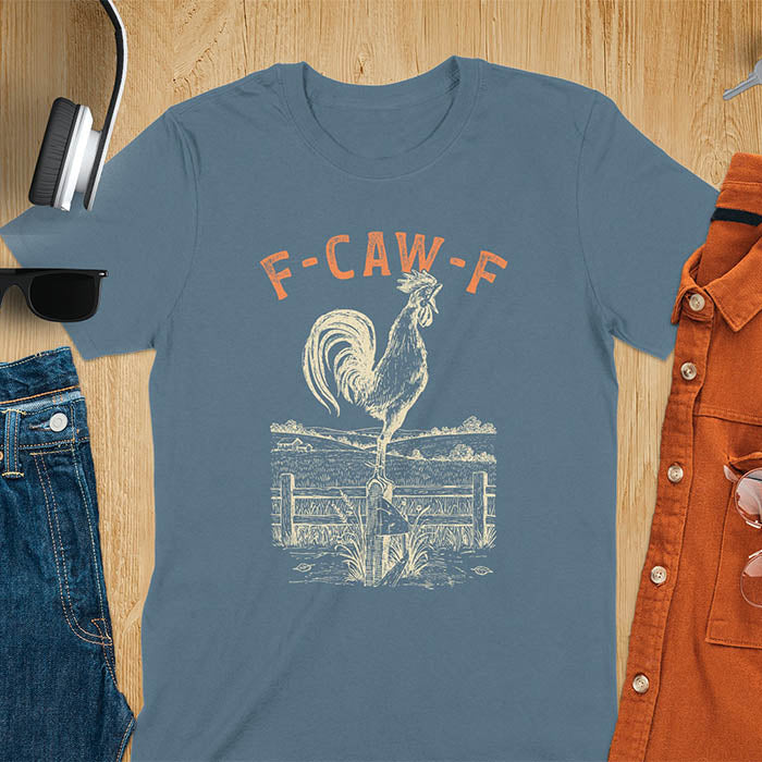 Indigo Blue t-shirt with F-CAW-F text and detailed rooster illustration standing on wooden fence in vintage farm scene style