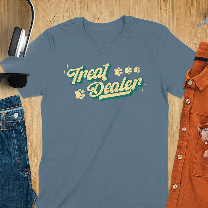 Indigo blue t-shirt with Treat Dealer text in retro script typography with green and yellow colors and paw print decorations