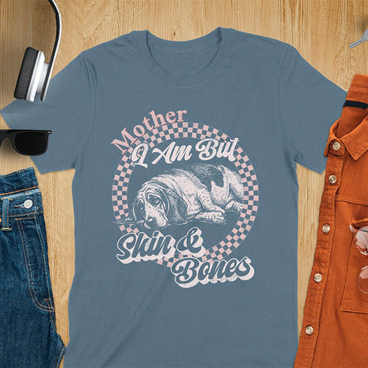 Indigo blue t-shirt with a vintage graphic of a basset hound lying down inside a retro checkered circle, with the text Mother I Am But Skin and Bones