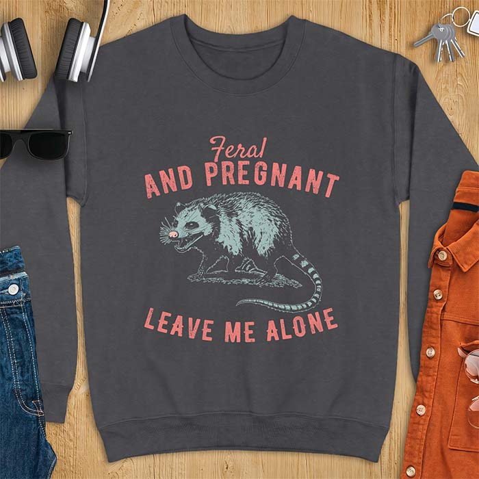 Dark Heather sweatshirt with a graphic of a hissing opossum baring its teeth with a striped tail, plus the text Feral And Pregnant Leave Me Alone.