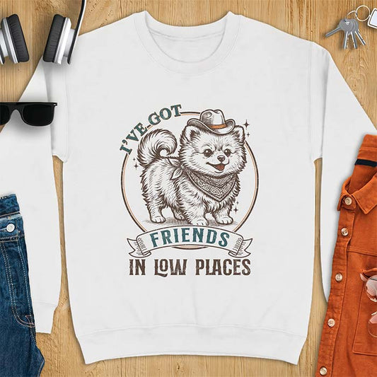 White sweatshirt with a vintage western illustration of a fluffy Pomeranian wearing a cowboy hat and a paisley bandana, with the text I've Got arched above it and Friends In Low Places below it