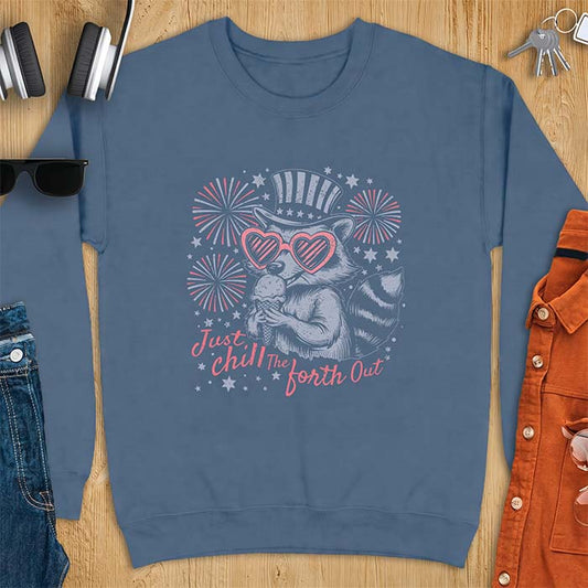 Indigo Blue sweatshirt with a graphic of a raccoon in a striped top hat and heart-shaped sunglasses eating an ice cream cone in front of fireworks and stars, printed with the text Just Chill The Forth Out