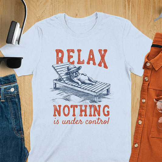 Light blue t-shirt featuring a bulldog wearing a straw hat lounging on a beach chair with text Relax Nothing Is Under Control in vintage red lettering