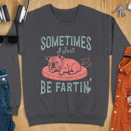 Dark Heather sweatshirt with a graphic of a sleeping English Bulldog curled up on a dog bed with a fart cloud drawn behind it beside the text Sometimes I Just Be Fartin