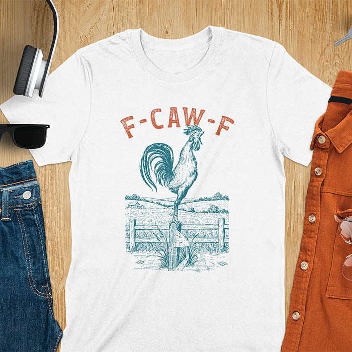 White t-shirt with F-CAW-F text and detailed rooster illustration standing on wooden fence in vintage farm scene style