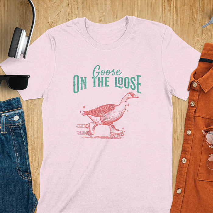 "Goose on the Loose" shirt features a goose on roller skates in motion, with vintage distressed font and colors. Perfect for fans of funny goose shirts, meme tees, sarcastic shirts, silly goose vibes, Y2K clothing, and animal lover gifts.