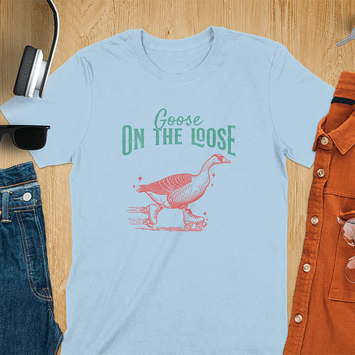 "Goose on the Loose" shirt features a goose on roller skates in motion, with vintage distressed font and colors. Perfect for fans of funny goose shirts, meme tees, sarcastic shirts, silly goose vibes, Y2K clothing, and animal lover gifts.