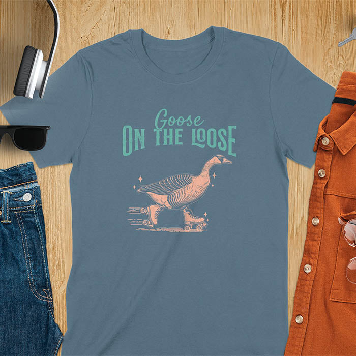 "Goose on the Loose" shirt features a goose on roller skates in motion, with vintage distressed font and colors. Perfect for fans of funny goose shirts, meme tees, sarcastic shirts, silly goose vibes, Y2K clothing, and animal lover gifts.