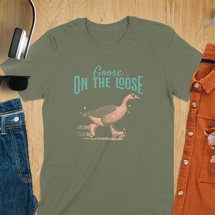 "Goose on the Loose" shirt features a goose on roller skates in motion, with vintage distressed font and colors. Perfect for fans of funny goose shirts, meme tees, sarcastic shirts, silly goose vibes, Y2K clothing, and animal lover gifts.