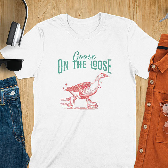 "Goose on the Loose" shirt features a goose on roller skates in motion, with vintage distressed font and colors. Perfect for fans of funny goose shirts, meme tees, sarcastic shirts, silly goose vibes, Y2K clothing, and animal lover gifts.