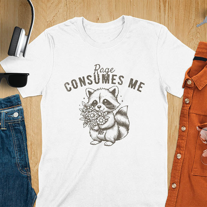 A t-shirt featuring a raccoon holding a bouquet of flowers. Text: Rage CONSUMES ME in a bold, arched font. This dark humor tee is a mental health meme and raccoon meme design. A weirdcore funny and weird funny shirt for a funny gag gift. A raccoon cuteness design, this is one of those shirts that go hard, a unisex and comfortable trendy tee. An animal person gift or girlfriend friend gift, a mom gift alternative.