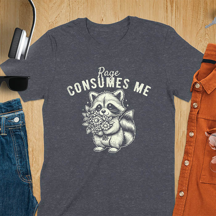 A t-shirt featuring a raccoon holding a bouquet of flowers. Text: Rage CONSUMES ME in a bold, arched font. This dark humor tee is a mental health meme and raccoon meme design. A weirdcore funny and weird funny shirt for a funny gag gift. A raccoon cuteness design, this is one of those shirts that go hard, a unisex and comfortable trendy tee. An animal person gift or girlfriend friend gift, a mom gift alternative.