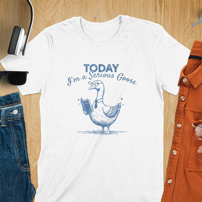 Featuring a retro vintage design with a distressed texture effect, this meme graphic tee showcases a dapper goose standing tall with a tie, collar, spectacles, and an open book in its wing, paired with the cheeky text, Today I’m a Serious Goose.