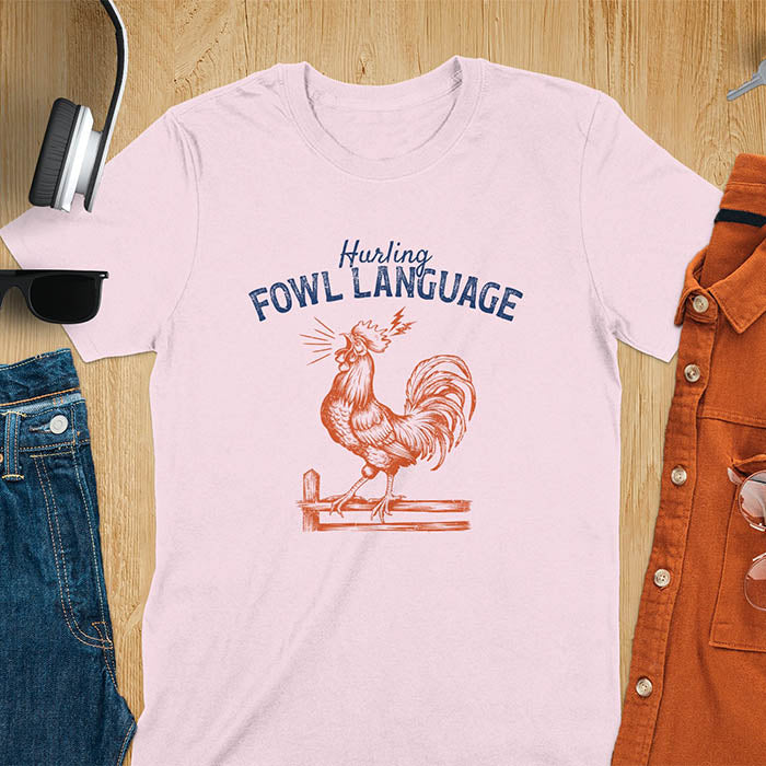 Vintage t-shirt with line art drawing of a chicken rooster standing on a fence in a farm crowing with exaggerated open beak. The design gives a fun and quirky vibe. Text says hurling fowl language.