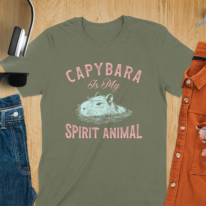 The design features a blue illustration of a capybara's head partly submerged in water and the text "CAPYBARA Is My SPIRIT ANIMAL" in red. This playful and trendy statement captures the calm and social nature of the capybara.