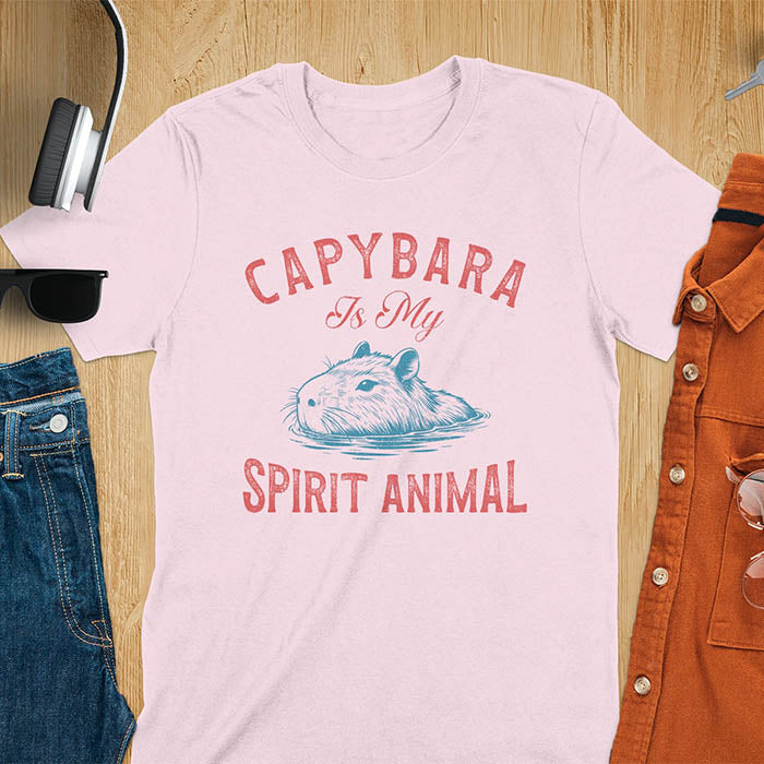 The design features a blue illustration of a capybara's head partly submerged in water and the text "CAPYBARA Is My SPIRIT ANIMAL" in red. This playful and trendy statement captures the calm and social nature of the capybara.