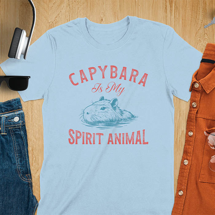The design features a blue illustration of a capybara's head partly submerged in water and the text "CAPYBARA Is My SPIRIT ANIMAL" in red. This playful and trendy statement captures the calm and social nature of the capybara.