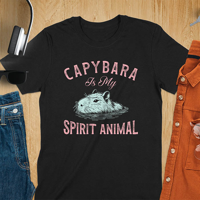 The design features a blue illustration of a capybara's head partly submerged in water and the text "CAPYBARA Is My SPIRIT ANIMAL" in red. This playful and trendy statement captures the calm and social nature of the capybara.