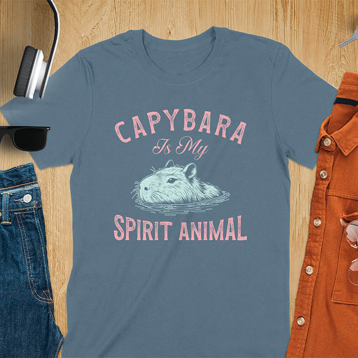The design features a blue illustration of a capybara's head partly submerged in water and the text "CAPYBARA Is My SPIRIT ANIMAL" in red. This playful and trendy statement captures the calm and social nature of the capybara.