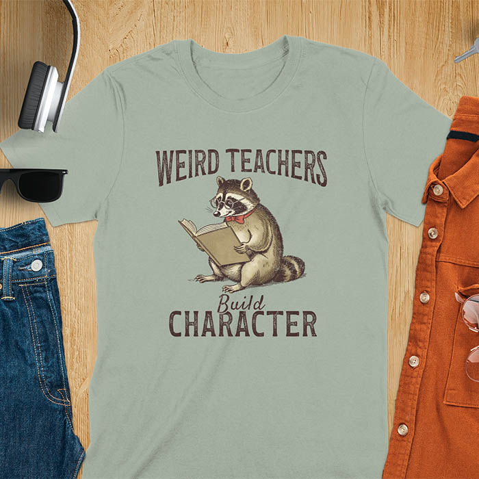 Weird Teachers Build Character shirt featuring a raccoon reading a book with glasses and a red bow tie. Vintage distressed font and brownish monotone give it a retro look. Perfect back-to-school shirt, funny teacher gift, or teacher appreciation tee.