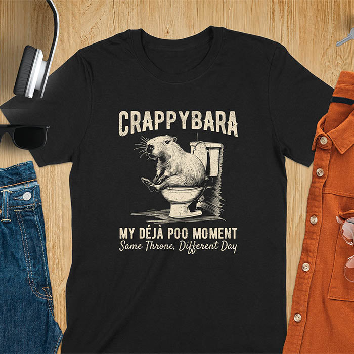 A humorous graphic of a capybara sitting on a toilet with the text Crappybara above and Déjà Poo Moment: same throne, different day below. A funny design for animal and meme lovers.