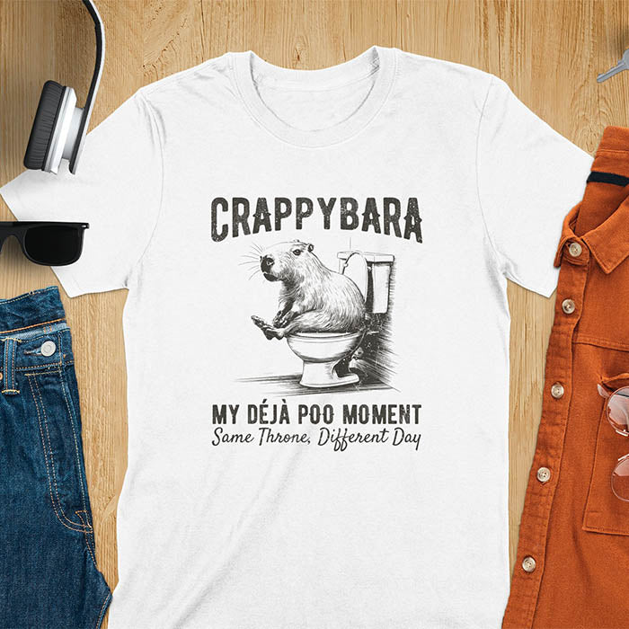 A humorous graphic of a capybara sitting on a toilet with the text Crappybara above and Déjà Poo Moment: same throne, different day below. A funny design for animal and meme lovers.