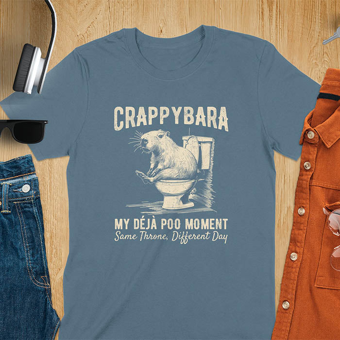 A humorous graphic of a capybara sitting on a toilet with the text Crappybara above and Déjà Poo Moment: same throne, different day below. A funny design for animal and meme lovers.