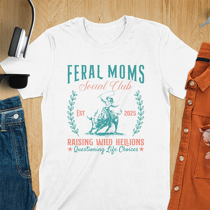 A t-shirt with a cowgirl riding a bucking bull. Text: Feral Moms SOCIAL CLUB above and Raising HELLIONS, questioning life choices below. This unhinged t-shirts design features a cowgirl mom on a rodeo bucking bull, a weird meme shirt for a feral mom gift. A retro inspired design, one of those shirts that go hard, a mama outfit or feral wife gift. A mom gift or gift for new mom for a western mama.