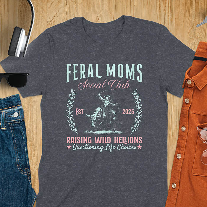 A t-shirt with a cowgirl riding a bucking bull. Text: Feral Moms SOCIAL CLUB above and Raising HELLIONS, questioning life choices below. This unhinged t-shirts design features a cowgirl mom on a rodeo bucking bull, a weird meme shirt for a feral mom gift. A retro inspired design, one of those shirts that go hard, a mama outfit or feral wife gift. A mom gift or gift for new mom for a western mama.