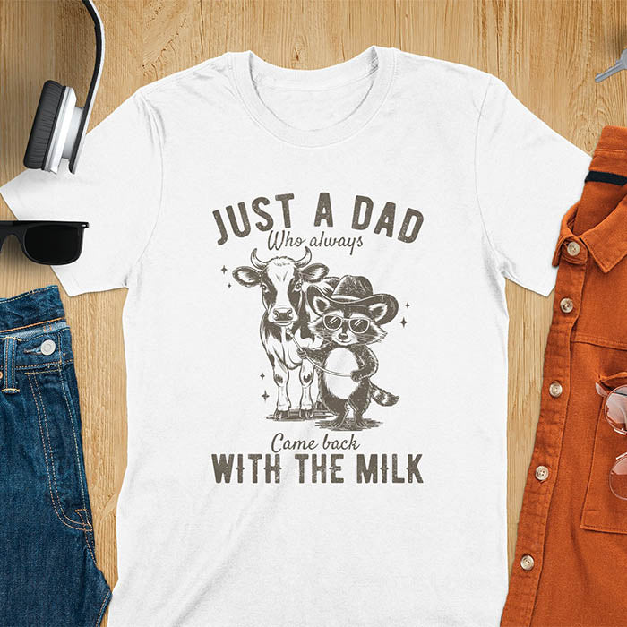 A t-shirt with a raccoon wearing a cowboy hat and sunglasses, holding a leash to a cow. Text: Just a Dad WHO ALWAYS above and Came Back WITH THE MILK below. This funny raccoon shirt features funny graphics, a dad t shirt for a funny fathers day or fathers day gift. A funny shirt for dad or gift for dad, a husband gift or father in law gifts. Could be used for a dad announcement, expectant dad, or godfather proposal.