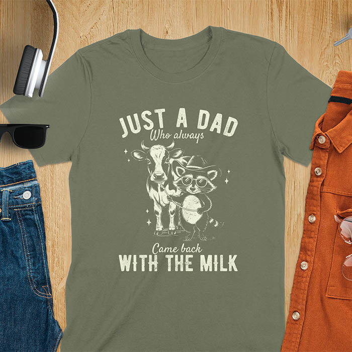 A t-shirt with a raccoon wearing a cowboy hat and sunglasses, holding a leash to a cow. Text: Just a Dad WHO ALWAYS above and Came Back WITH THE MILK below. This funny raccoon shirt features funny graphics, a dad t shirt for a funny fathers day or fathers day gift. A funny shirt for dad or gift for dad, a husband gift or father in law gifts. Could be used for a dad announcement, expectant dad, or godfather proposal.