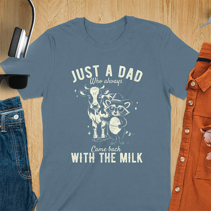 A t-shirt with a raccoon wearing a cowboy hat and sunglasses, holding a leash to a cow. Text: Just a Dad WHO ALWAYS above and Came Back WITH THE MILK below. This funny raccoon shirt features funny graphics, a dad t shirt for a funny fathers day or fathers day gift. A funny shirt for dad or gift for dad, a husband gift or father in law gifts. Could be used for a dad announcement, expectant dad, or godfather proposal.