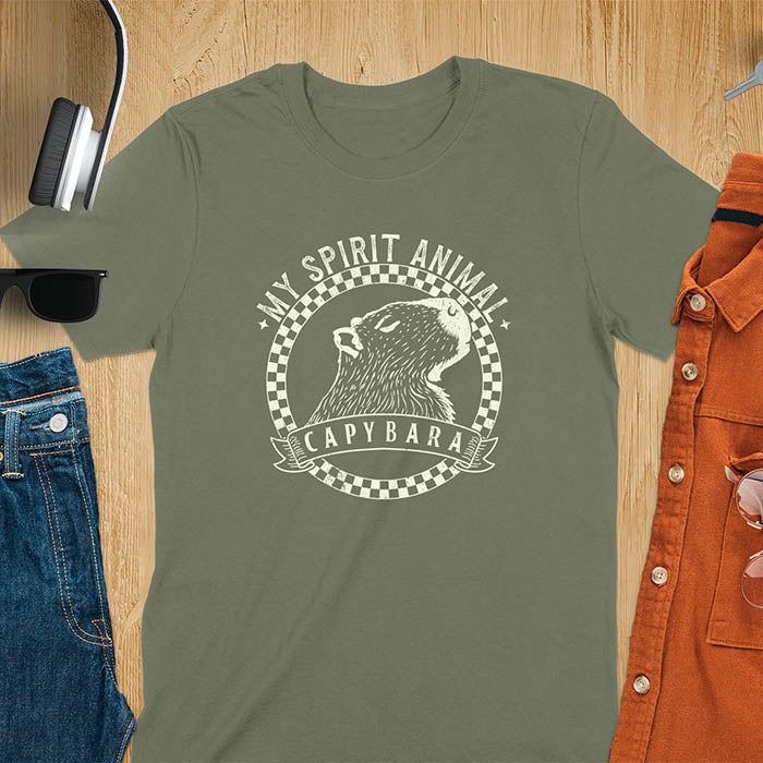 A T-shirt with a graphic of a capybara inside a checkered circle. Above the capybara, text reads "MY SPIRIT ANIMAL," and below, a banner says "CAPYBARA."