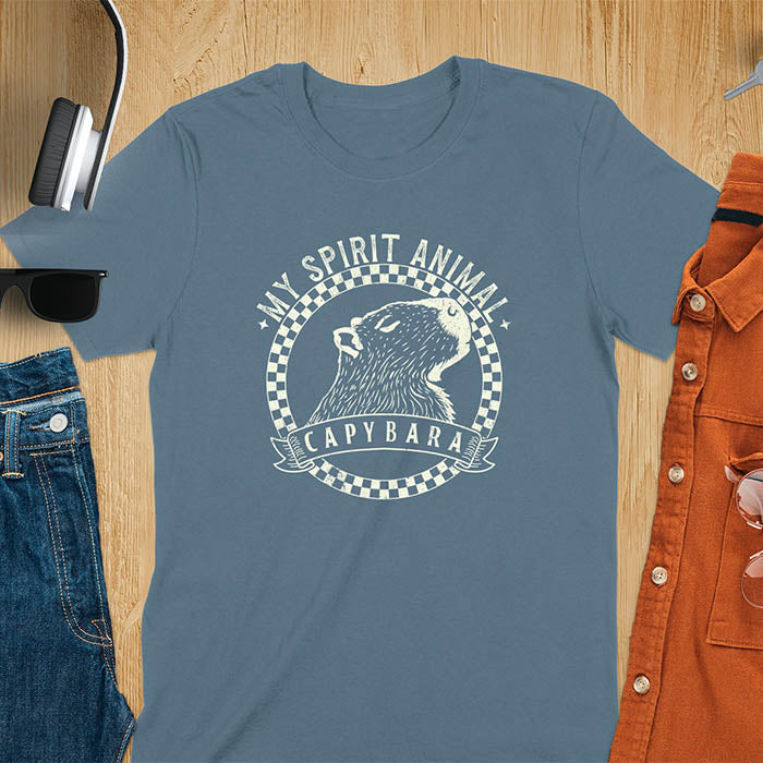 A T-shirt with a graphic of a capybara inside a checkered circle. Above the capybara, text reads "MY SPIRIT ANIMAL," and below, a banner says "CAPYBARA."