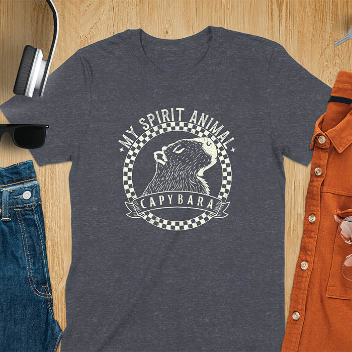 A T-shirt with a graphic of a capybara inside a checkered circle. Above the capybara, text reads "MY SPIRIT ANIMAL," and below, a banner says "CAPYBARA."