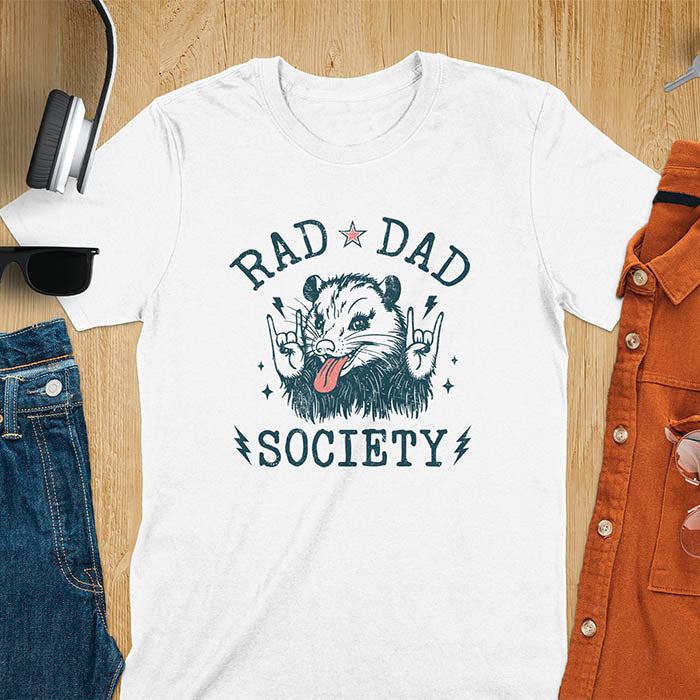 A t-shirt with an opossum sticking its tongue out and giving rock-on hand signs. Text: "RAD DAD" above and "SOCIETY" below. This rad dad society tee is for the cool dad club. A dad humor gift and cool dad tee-shirt, a daddie's t shirt or dad birthday shirt. A first father's day or fathers day gifts, a new daddy gift or gift for daddie. A pet dad gift for a husband outfit.