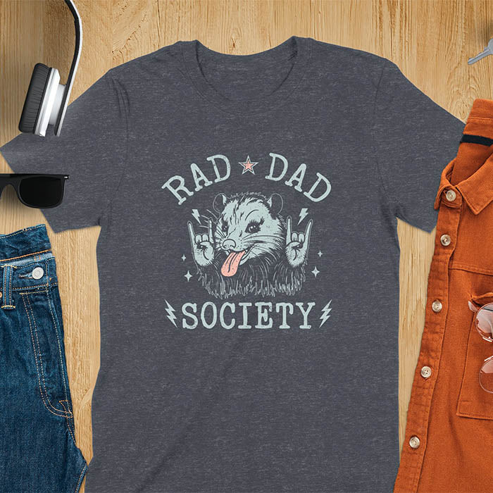 A t-shirt with an opossum sticking its tongue out and giving rock-on hand signs. Text: "RAD DAD" above and "SOCIETY" below. This rad dad society tee is for the cool dad club. A dad humor gift and cool dad tee-shirt, a daddie's t shirt or dad birthday shirt. A first father's day or fathers day gifts, a new daddy gift or gift for daddie. A pet dad gift for a husband outfit.