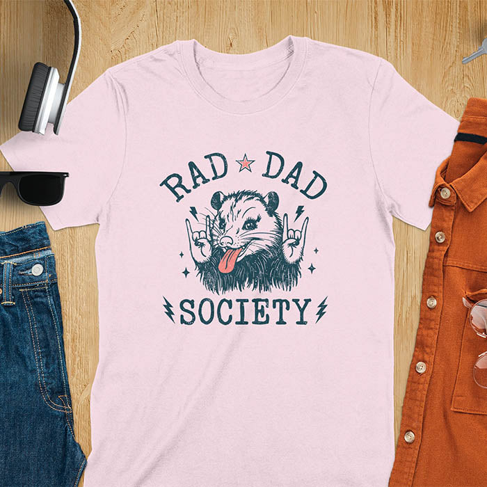 A t-shirt with an opossum sticking its tongue out and giving rock-on hand signs. Text: "RAD DAD" above and "SOCIETY" below. This rad dad society tee is for the cool dad club. A dad humor gift and cool dad tee-shirt, a daddie's t shirt or dad birthday shirt. A first father's day or fathers day gifts, a new daddy gift or gift for daddie. A pet dad gift for a husband outfit.