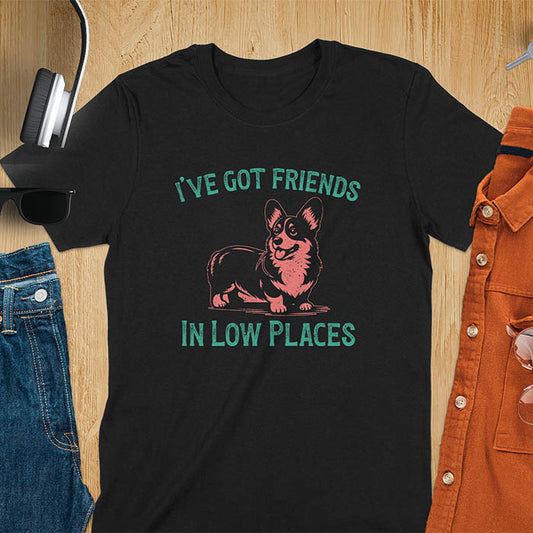 Our vintage-inspired design features a cute corgi silhouette with facial details. Text above it says 'I've Got Friends' and below it says ''In Low Places.' With its retro vibe and distressed texture, this tee adds a touch of nostalgia to your wardrobe.