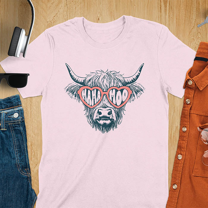 A t-shirt featuring a fluffy highland cow face with long horns, wearing pink heart-shaped sunglasses spelling MAMA MOO. Below the cow, Veronica is written in script font. This retro mom tee-shirt design is a cute cow highlander for mama mom life. A funny animal mom tee for an expecting mom or pregnant mom gift, ideal for a pregnancy announcement or pregnancy reveal. A great mom gift or Mother days gift, or a new mom gift for a gift for wife. The name can be personalized.