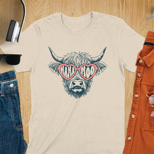A t-shirt featuring a fluffy highland cow face with long horns, wearing pink heart-shaped sunglasses spelling MAMA MOO. Below the cow, Veronica is written in script font. This retro mom tee-shirt design is a cute cow highlander for mama mom life. A funny animal mom tee for an expecting mom or pregnant mom gift, ideal for a pregnancy announcement or pregnancy reveal. A great mom gift or Mother days gift, or a new mom gift for a gift for wife. The name can be personalized.