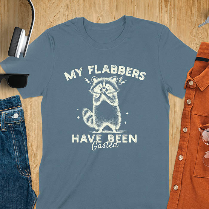 A t-shirt featuring a raccoon with wide eyes and paws covering its mouth. Text: MY FLABBERS above and HAVE BEEN Gasted below in a distressed font. This sarcastic tee-shirt features a funny raccoon with kawaiiness cuteness, a genz meme tee or anxiety tshirt. A depress meme and weirdcore memes design, a funny gag gift for sad core fans. This is one of those shirts that go hard, a trash panda design.