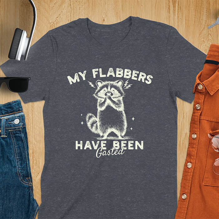 A t-shirt featuring a raccoon with wide eyes and paws covering its mouth. Text: MY FLABBERS above and HAVE BEEN Gasted below in a distressed font. This sarcastic tee-shirt features a funny raccoon with kawaiiness cuteness, a genz meme tee or anxiety tshirt. A depress meme and weirdcore memes design, a funny gag gift for sad core fans. This is one of those shirts that go hard, a trash panda design.